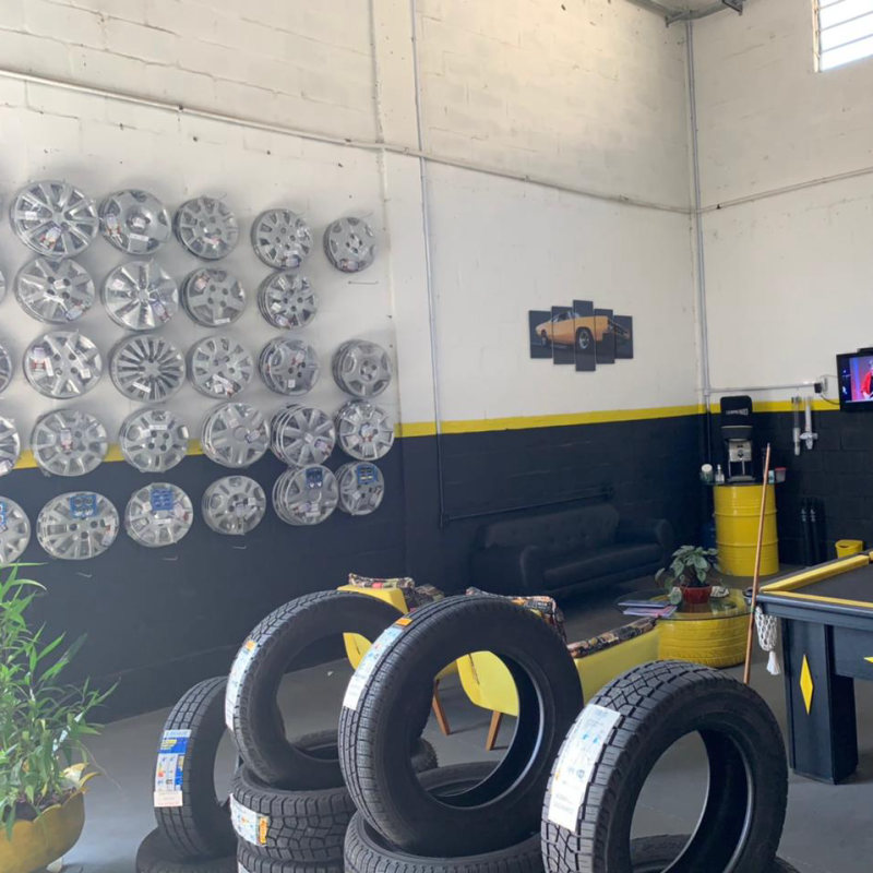 Parede com rodas expostas, pneus no chão e mesa de sinuca na sala de espera