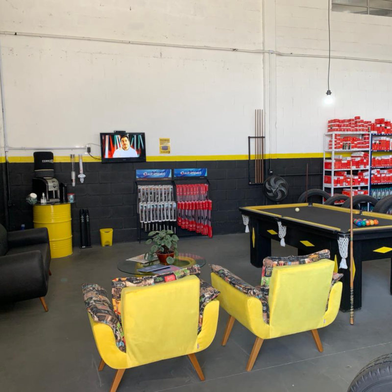 Sala de espera com poltronas amarelas, sofá e mesa de sinuca